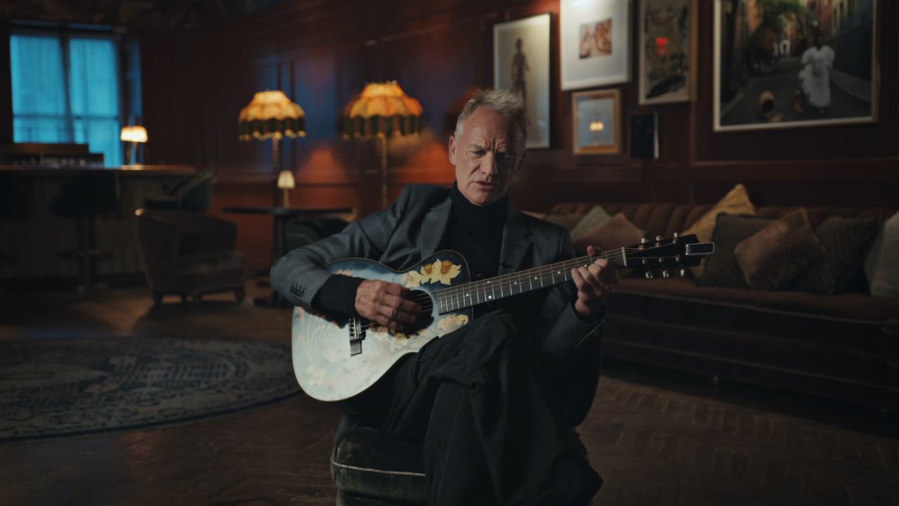 Sintg playing guitar on a couch